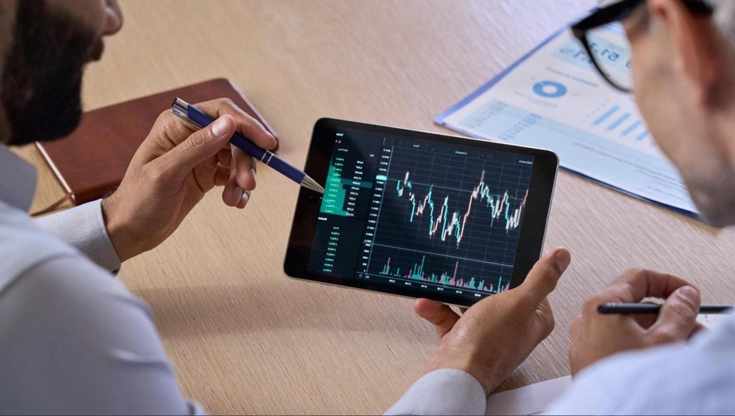 Analyst pointing at a tablet showing real-time monitoring charts and alerts